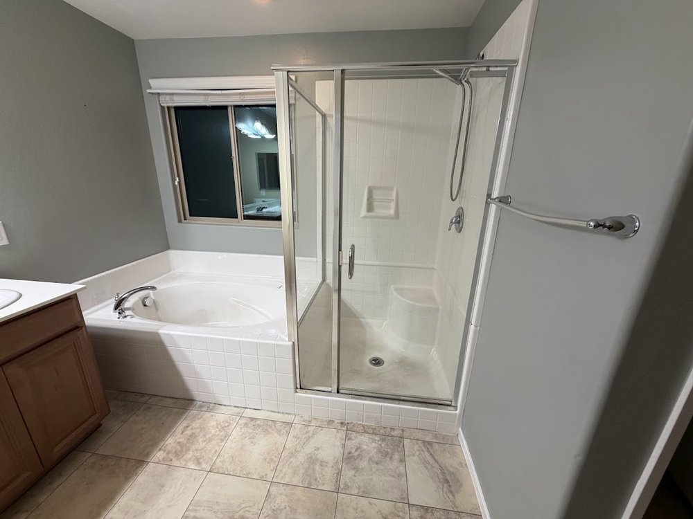 A clean primary bathroom with a sparkling shower and tub